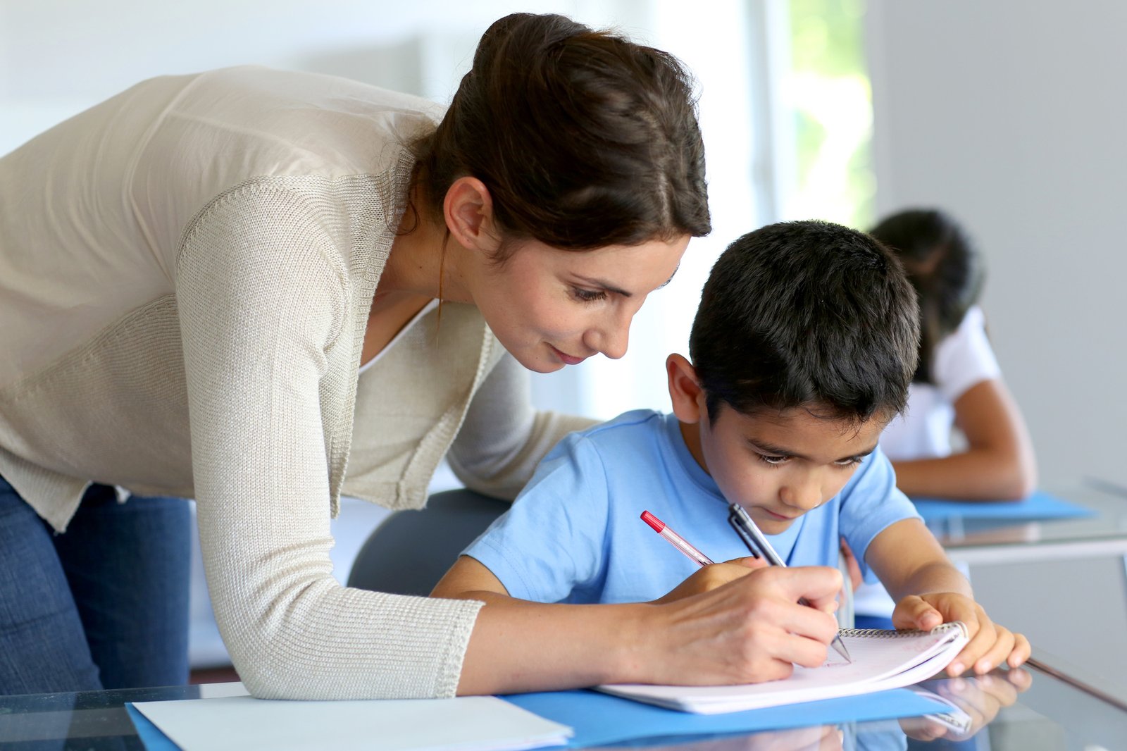 Teacher helping young boy with writing lesson